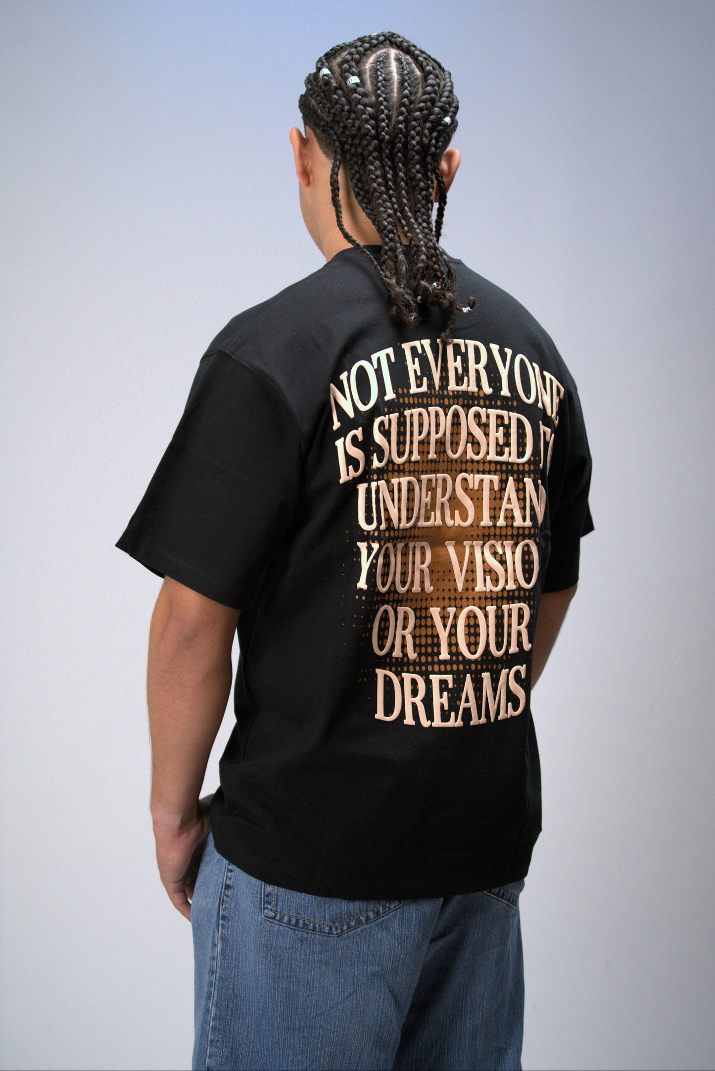 Person wearing a black t-shirt with a motivational quote on the back against a plain background