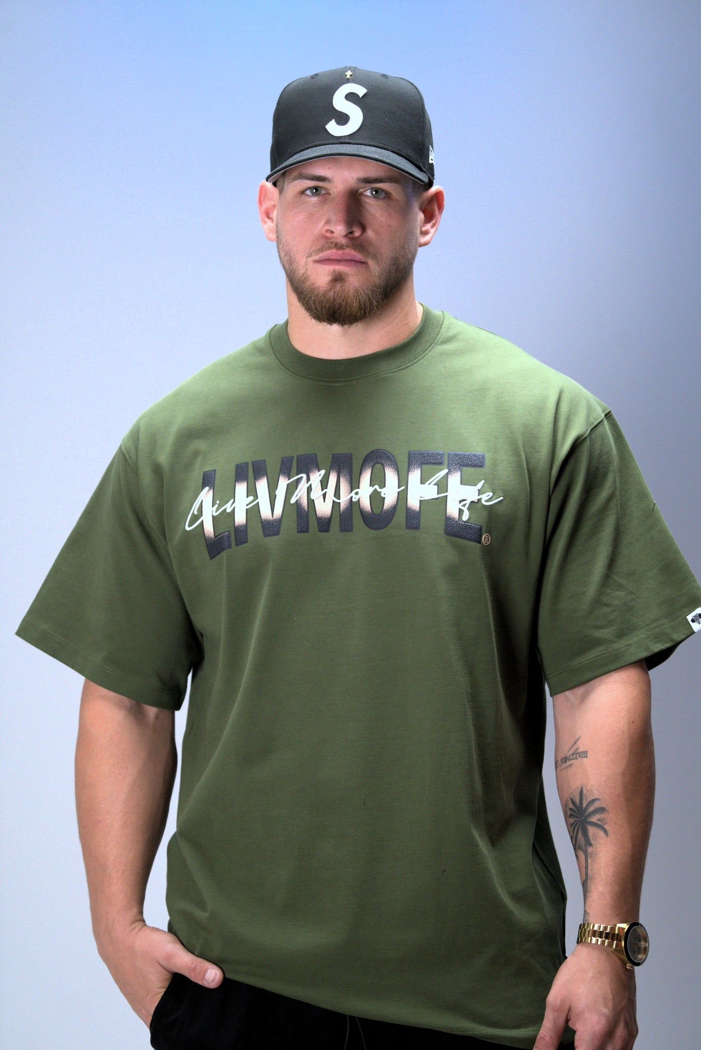 Man wearing a green t-shirt with text and a cap on a light blue background