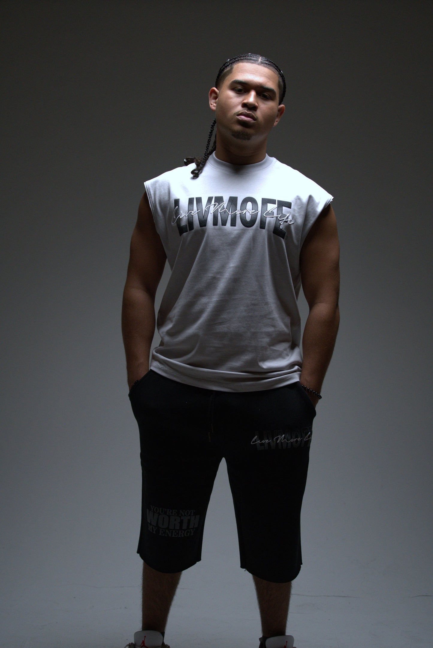 Man wearing a gray sleeveless shirt with 'LIVMOFE' text and black shorts on a dark background
