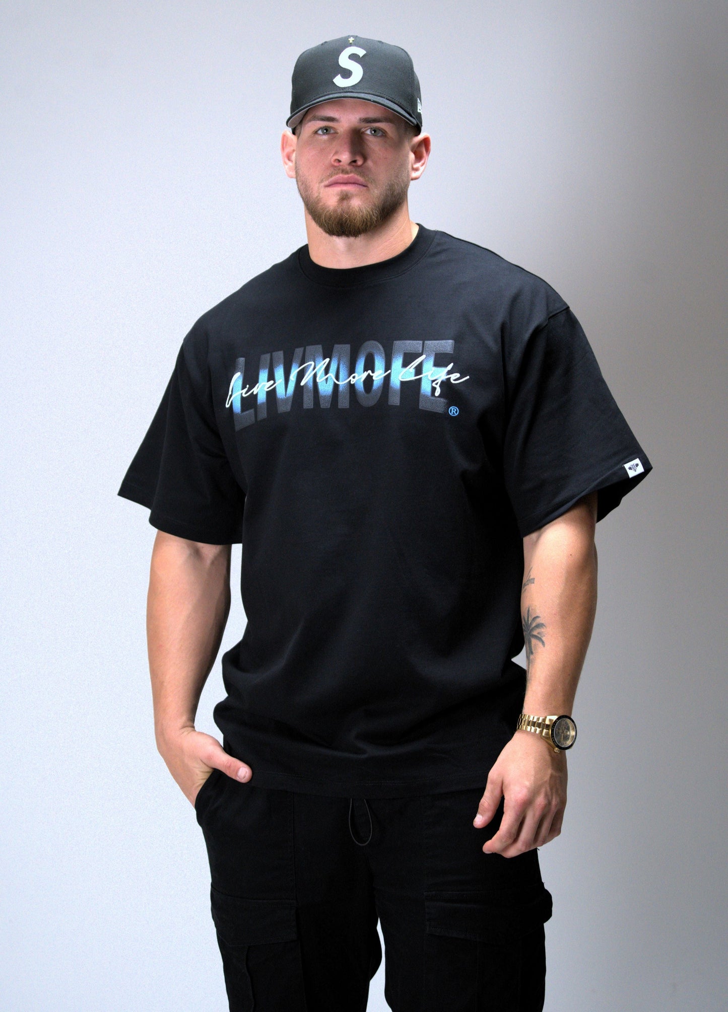 Man wearing a black t-shirt with text and a cap on a gray background