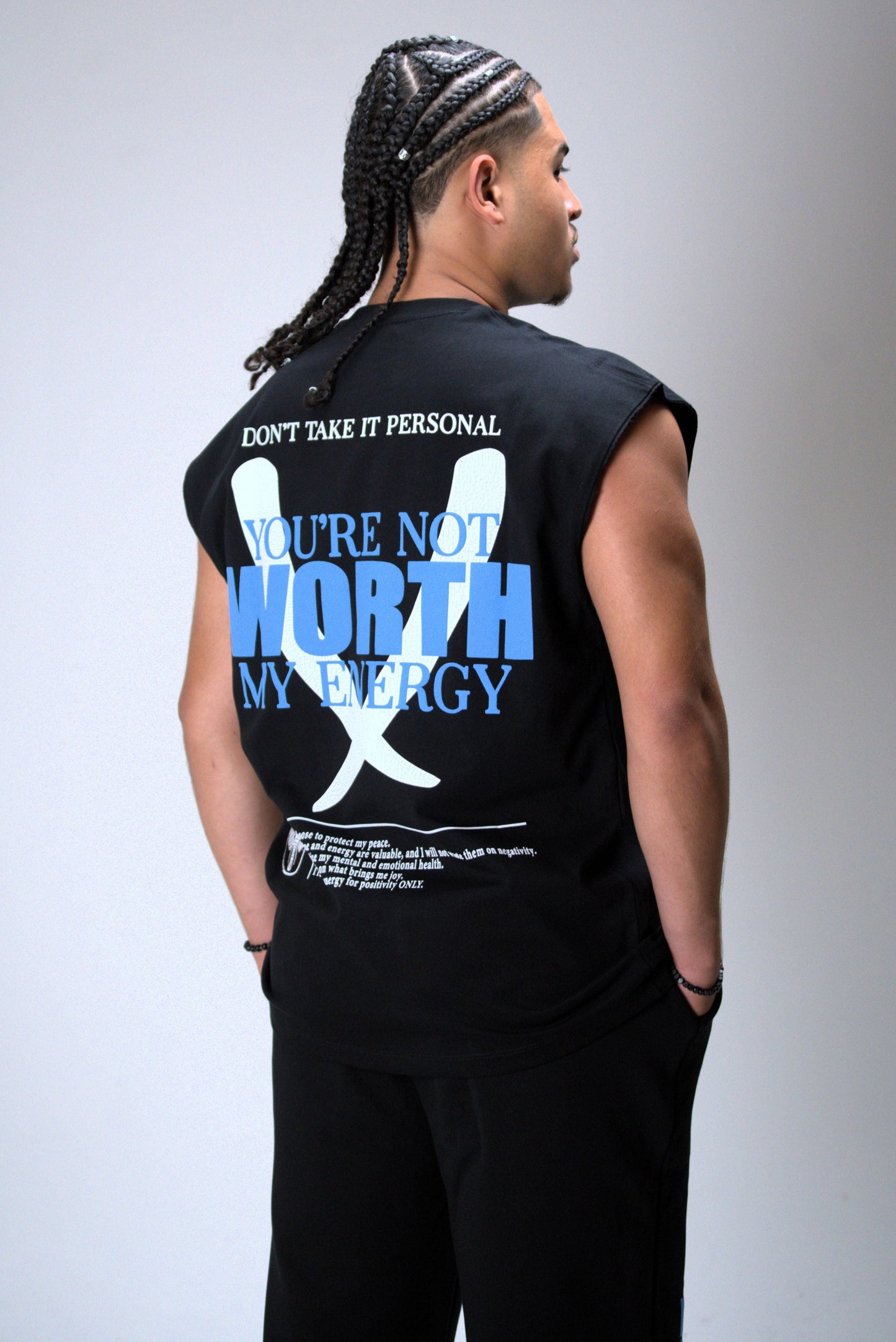 Person wearing a black sleeveless shirt with text and graphics on the back against a gray background