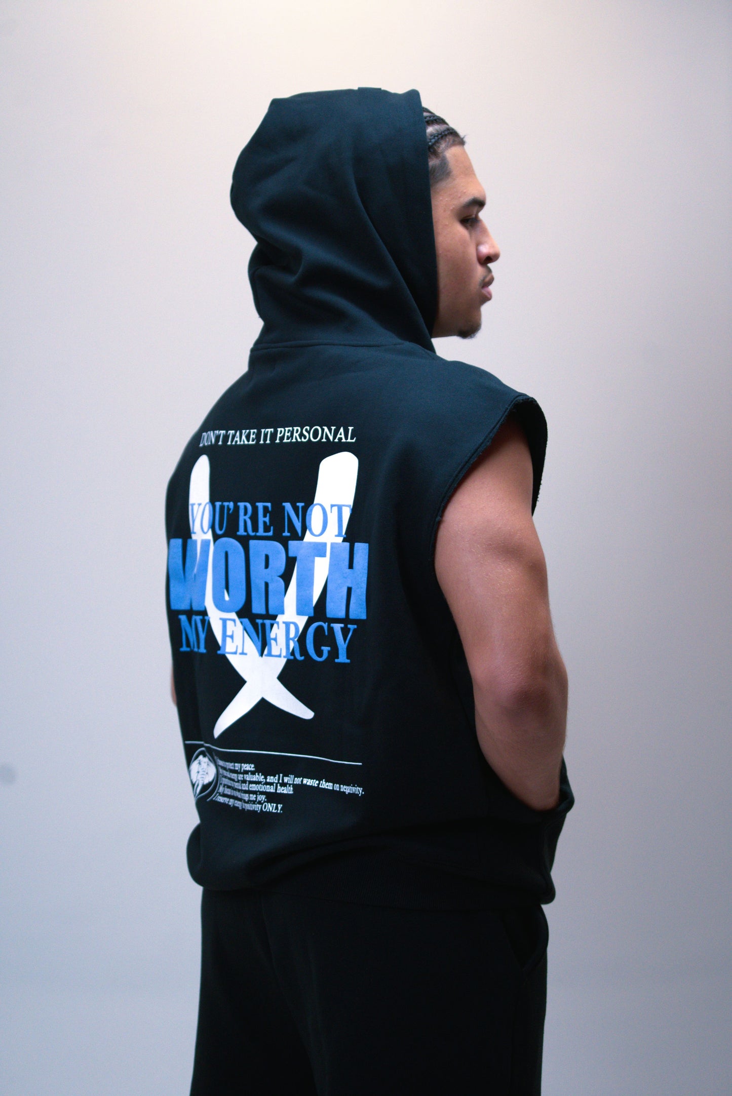 Person wearing a black sleeveless hoodie with text and graphics on the back against a plain background
